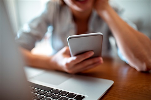 Person holding a phone and using the computer