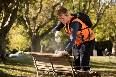 A worker disinfects a park bench.