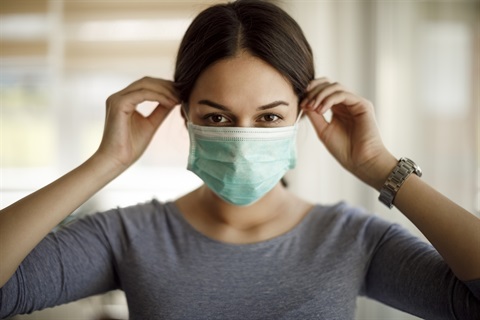 A person putting on a single-use face mask.