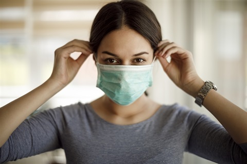 A person putting on a single-use face mask.