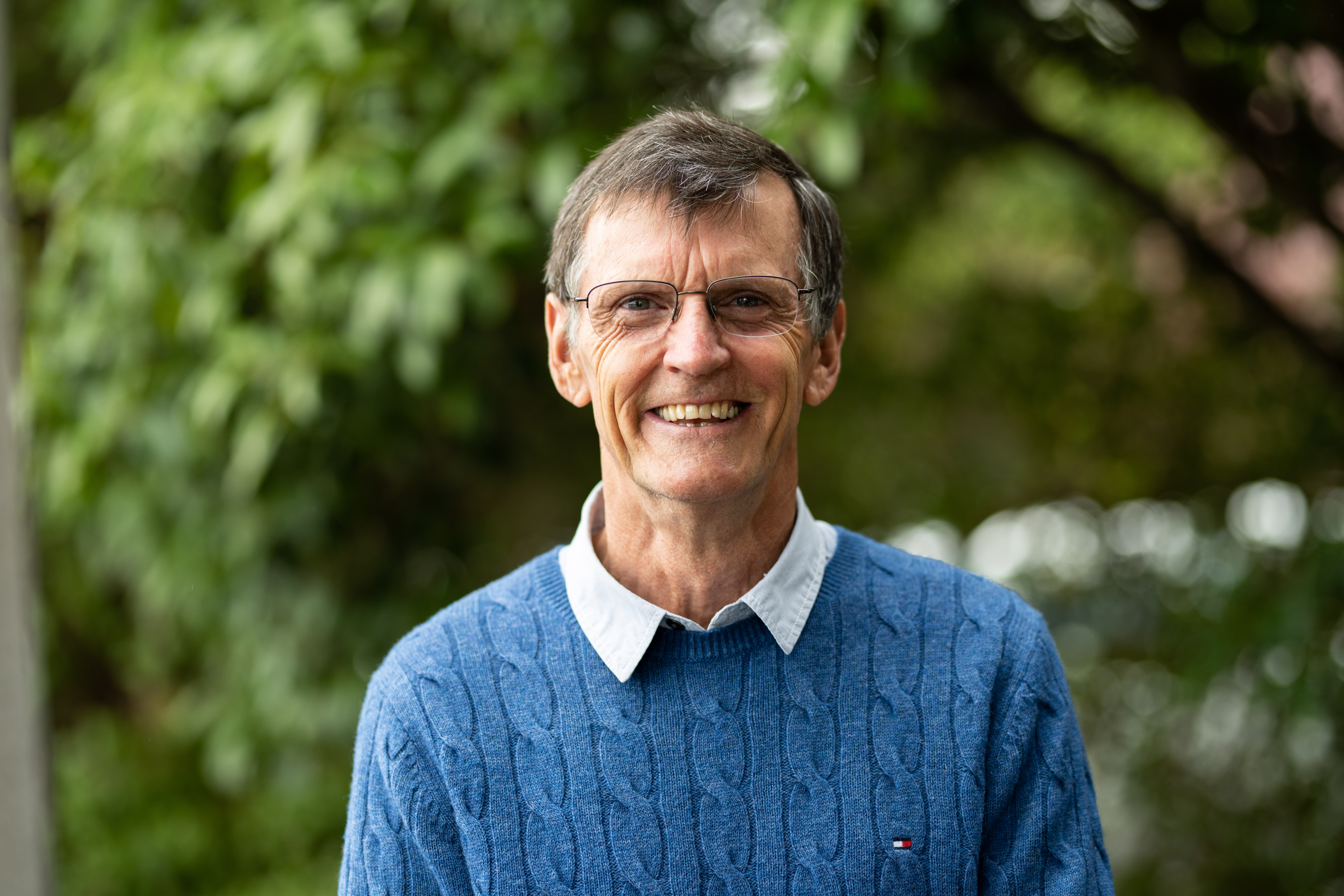 Andrew Fullagar stands in front of a tree, smiling.