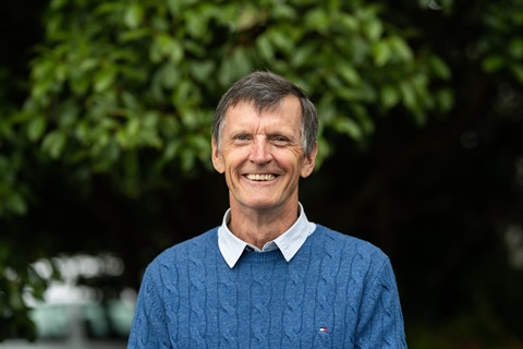 Andrew Fullagar stands in front of a tree, smiling.