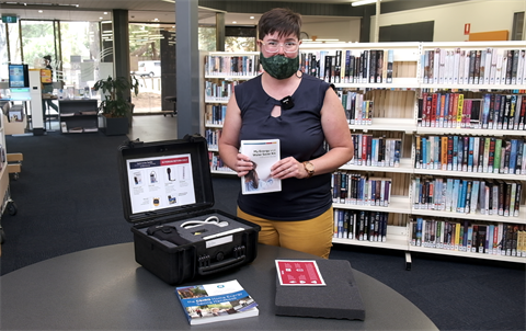 A Council officer stands in a library with a home energy testing kit.