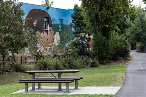 A bench seat in Lilydale with a mural in the background.