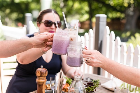 A group of people clinking smoothie jars together. Photo by Cathy Ronalds.