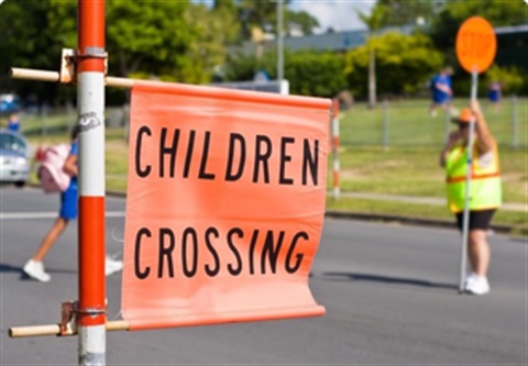 School crossing supervisor and child crossing the road