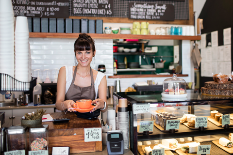 Person serving coffee over the counter in a cafe