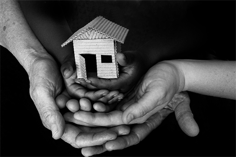 cardboard house in the hands of adults and small children