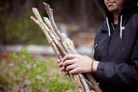 A person holding bundled sticks/branches.