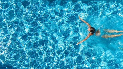 A person swimming in a pool, photo taken from overhead.