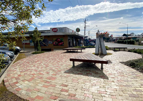 Wandin North's sitting area, with chairs and a sculpture in a brick plaza.
