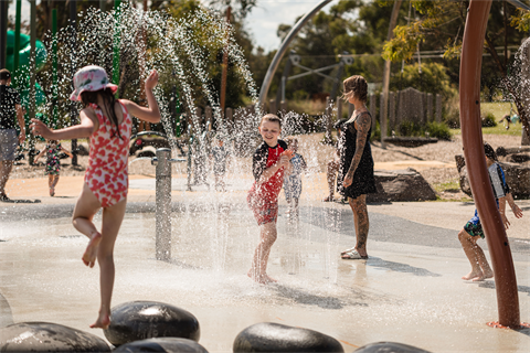 A photo of children and a parent at the Lillyale Lake water play park.