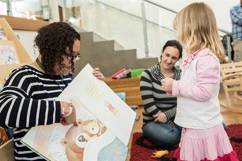 Volunteer reading a story to a young girl